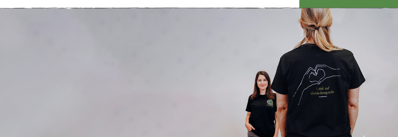 2 Frauen, von vorne und von hinten zu sehen, mit schwarzem T-Shirt mit der Aufschrift "I steh' auf Gebärdensprache"